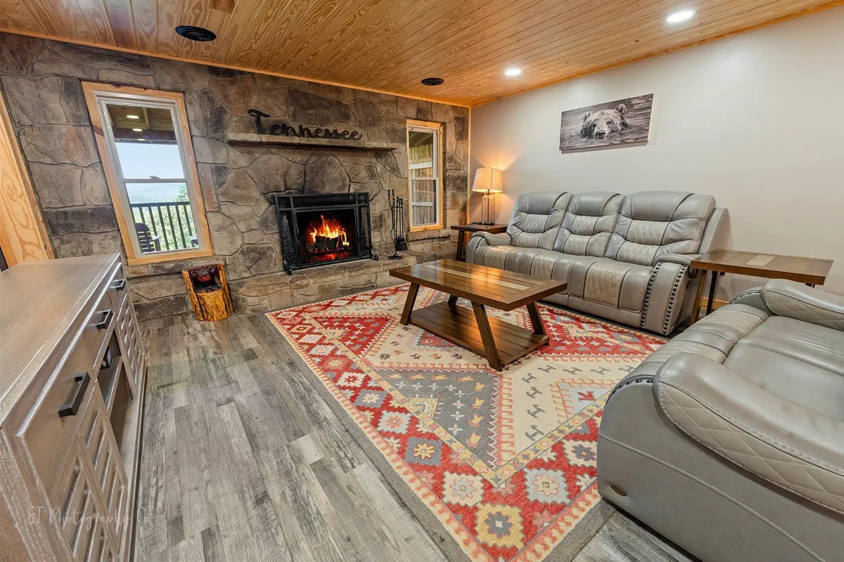 A cozy seating area with a fireplace, comfortable chairs, a textured rug, and a large window offering views and natural light. The setup is ideal for relaxation, conversation, and enjoying the mountain ambiance after a day of activities.