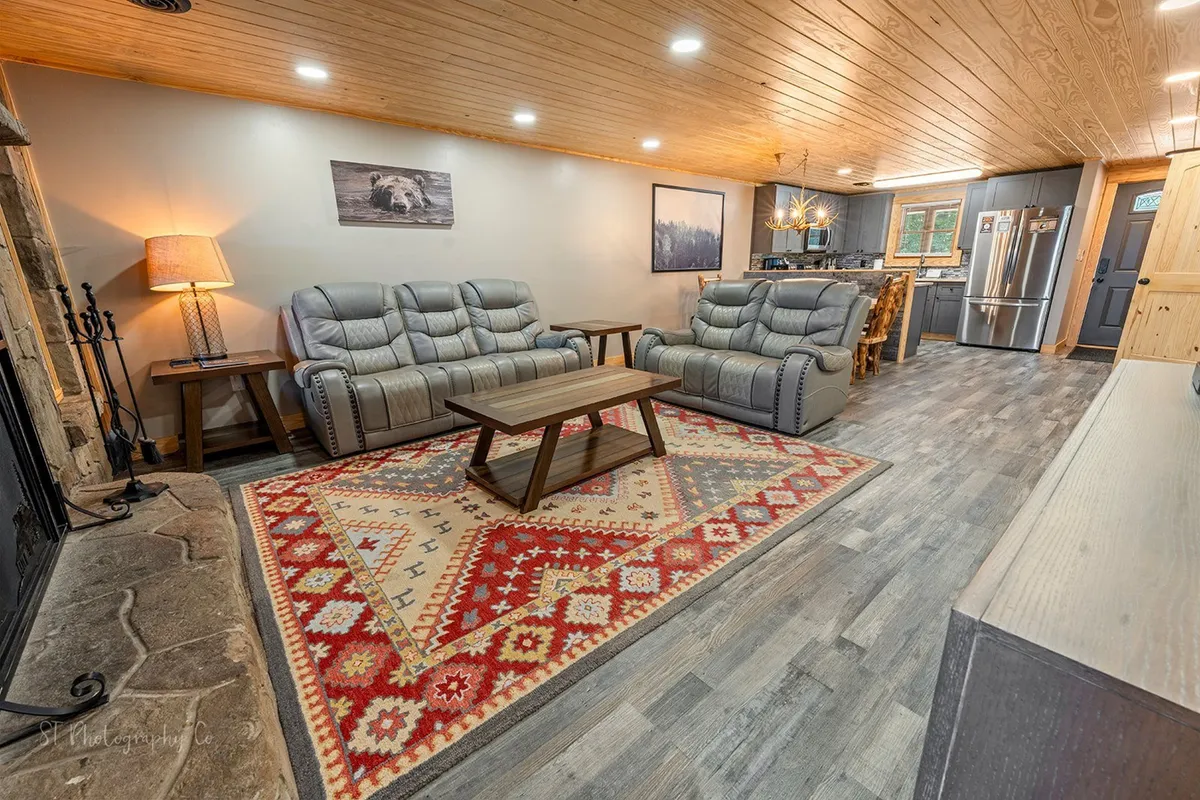 A cozy living room featuring a rustic stone fireplace, comfortable sofa set, coffee table, and tasteful artwork. Warm wood accents and soft textiles create an inviting atmosphere ideal for relaxing after a day of exploring the Smoky Mountains. The fireplace becomes a focal point for intimate evenings in colder seasons.
