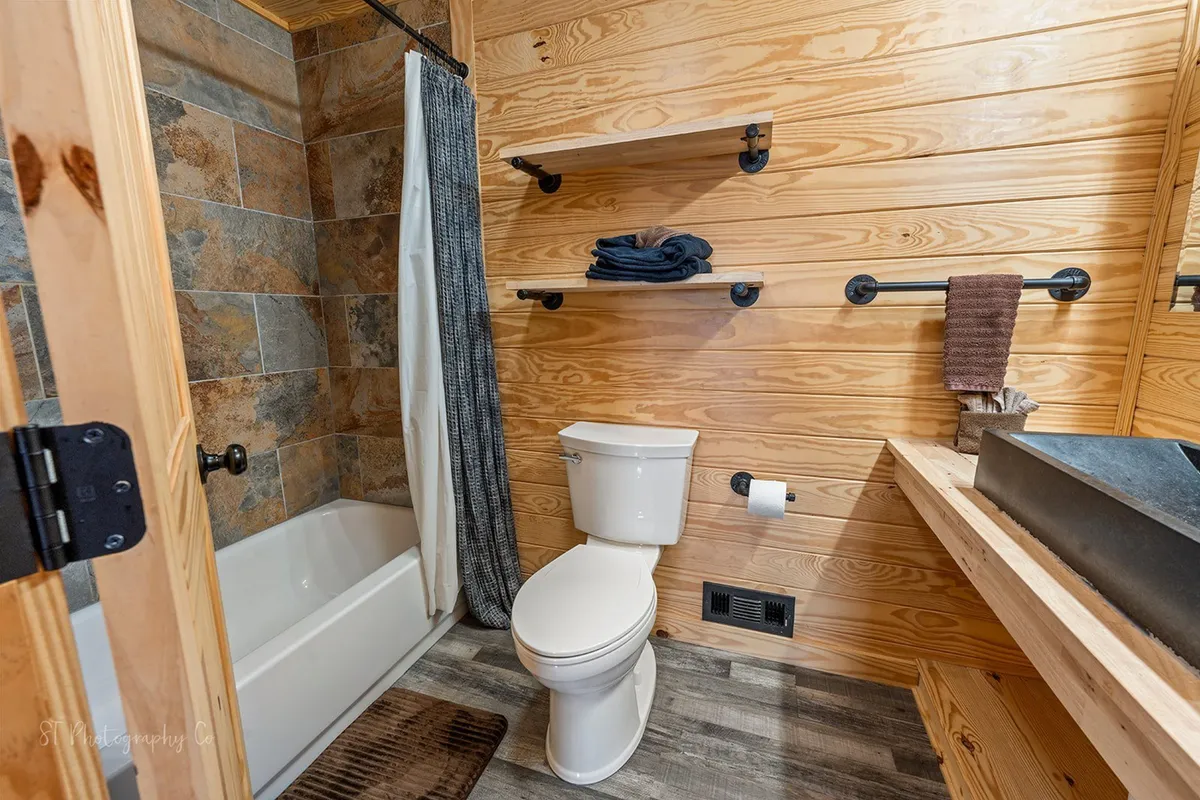 This image features a clean, relaxing full bathroom with a bathtub, toilet, shelves, and sink. The setting suggests a spot for unwinding and self-care after a day of outdoor activities, echoing the section’s emphasis on private bath amenities.