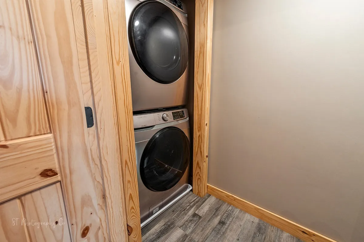 A practical laundry closet with washer and dryer tucked beneath wooden cabinetry, highlighting both convenience and efficient use of space for guests handling laundry needs during their stay.