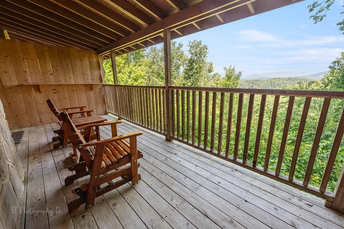A serene outdoor view from the porch, with rocking chairs facing out over lush greenery and a wooden railing, inviting guests to enjoy morning coffee or take in the sunrise. The setting is quiet and immersed in nature.